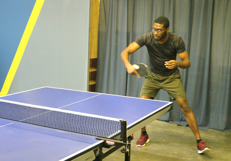 A man performing a table tennis backhand drive